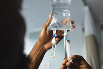 Close up of african american male doctor applying drip in hospital room