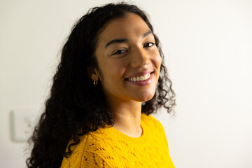 Portrait of happy biracial woman in yellow sweater at home