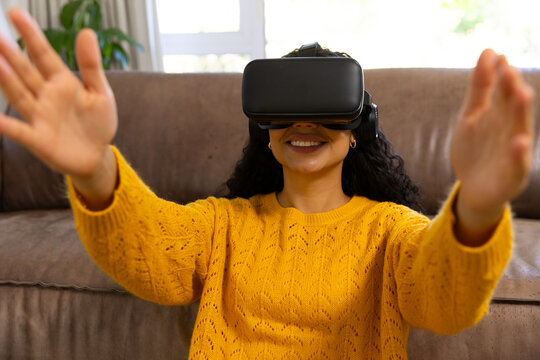 Happy biracial woman using vr headset at home