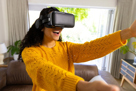 Happy biracial woman using vr headset at home - Powered by Adobe