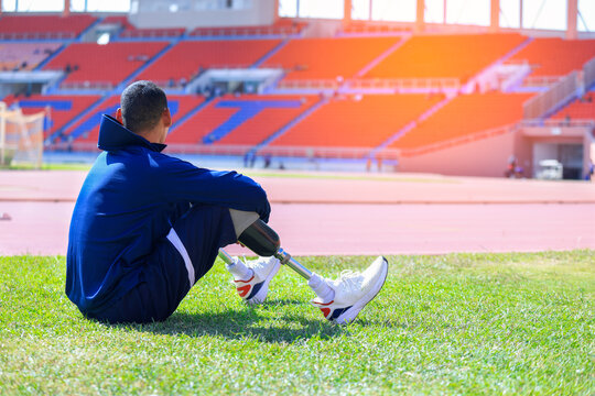 Asian para-athlete with prosthetic blades leg in stadium practicing workout for Paralympic running competition. Amputee sportsman runner practicing running workout. Disabled athlete man sport concept.