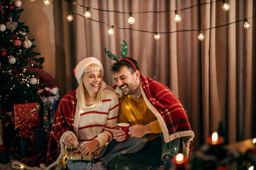 A jolly couple is opening presents and laughing at home on christmas and new year's eve.