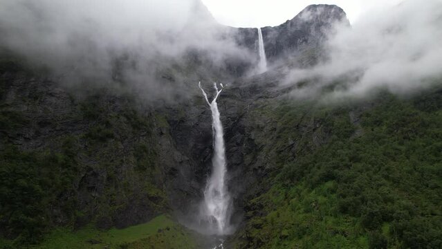 epic waterfall in clouds zoom out drone shot, double waterfall of Mardalsfossen in Norway
