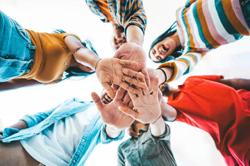 Community of millennial people stacking hands together - Multiracial college students putting their hands on top of each other - Human relationship, social, community and team building concept - obrazy, fototapety, plakaty