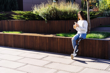 Female with prosthetic leg sitting in city. Disabled woman with prosthetic leg in red headphones,...