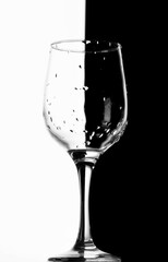 Wet wine glass on black and white half split background. High contrast.