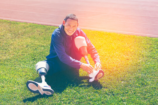 Asian para-athlete with prosthetic blades leg in stadium practicing workout for Paralympic running competition. Amputee sportsman runner practicing running workout. Disabled athlete man sport concept.
