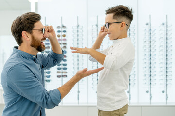 Smiling father and son in eyeglasses giving five high in optics - Powered by Adobe