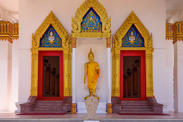 Statue of a Golden Buddha outside the doors of Wat Mongkhon Nimit Buddhist Temple, Phuket Old Town,...