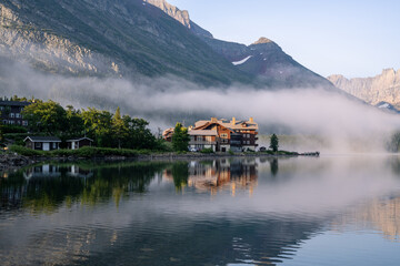 Historic, old style wooden structure on the edge of a mountain lake shrouded in fog and surrounded...