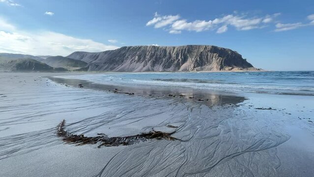 Small waves rolling on to the sandy beach on a sunny summer day, Barents Sea, Northern Norway