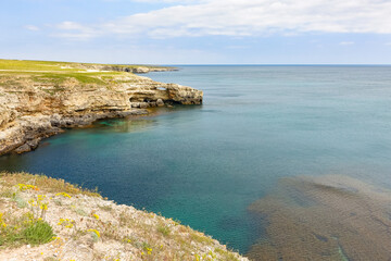 Fototapeta na wymiar Cape Tarkhankut on the Crimean peninsula. The rocky coast of the Dzhangul Reserve in the Crimea. The Black Sea. Turquoise sea water. Rocks and grottoes of Cape Tarkhankut.