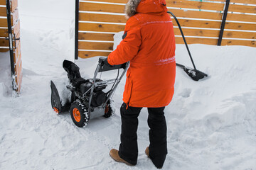 A man clear snow from backyard with snow blower. Winter season and snow blower equipment