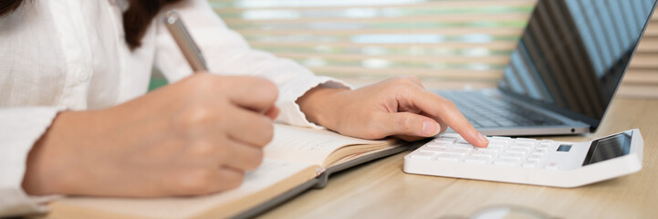 Asian woman taking notes in notebook while studying online in laptop at home, Video chat, Online communication , Stay home, New normal, Distance learning, Social distancing, Learn online..