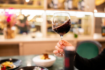man hand holding a glass with red wine in a restaurant