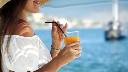 Closeup of beautiful woman drinking cocktail or juice with straw while enjoying summer vacation on...