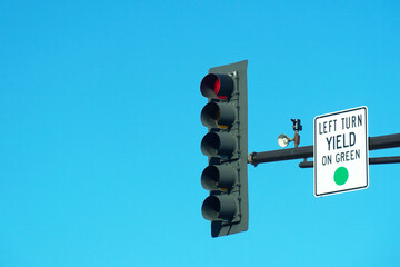 Red traffic light and LEFT TURN YIELD ON GREEN sign