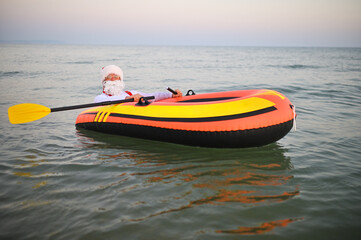 Santa in red suspenders floats on an inflatable boat against the background of the sea.