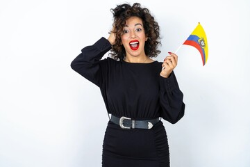 Young beautiful woman with curly hair wearing black dress and holding and Ecuador flag and...