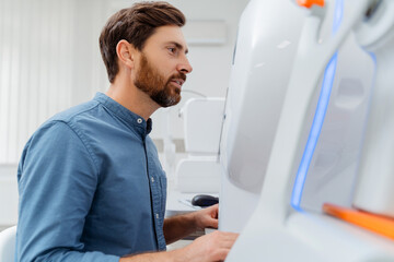 Male patient going to exam his eyesight with special equipment machine