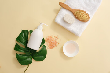 White pump bottle without label placed on a green leaf. A folded towel featured a hairbrush and foot scrubber brush. Blank label for natural beauty product promotion