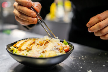 Chef cooking Caesar salad on restaurant kitchen