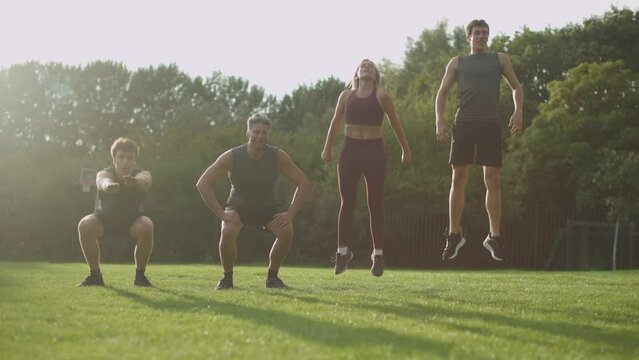 sporty family doing jump squats outdoors on grass