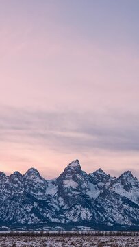 Vertical Timelapse of the Grand Teton Mountain Range during sunset with snow covered landscape in Wyoming.