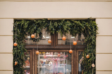 The natural bright green tree above the window opening is decorated with large orange decorative balls in the shape of oranges. New Year holidays concept. Handmade background.