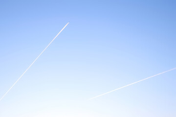 Two airplanes flying on deep blue sky with chemical direction trails, air transportation concept....