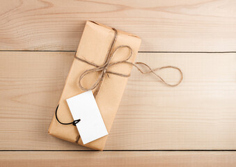 Gift Box Wrapped in Brown Recycled Paper With Congratulation on Wooden Table. Copy Space and Holiday Concept.