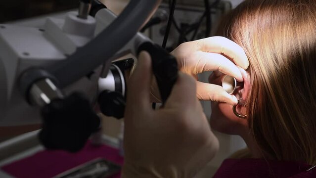 otolaryngologist conducts medical examination of ear with otoscope closeup