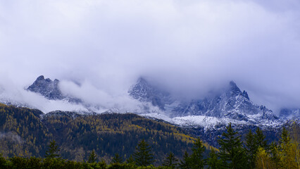 montagne enneigée dans la brume, avec colline d'arbres aux nuances de couleurs d'automne, ambiance mystérieuse