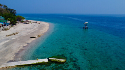 Top view of the beach of a tropical island. Aerial view of sandy beach, rock pier and lifeguard...