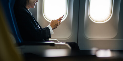 Traveling and technology. flying at first class. pretty young asian business woman using smartphone...