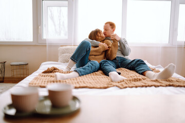 Portrait of a loving couple resting on the bed at home, hugging. A man and a woman enjoy the comfort of home, spending time together. Concept of love, relaxation.
