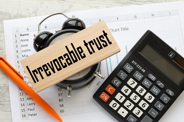 Irrevocable trust. text on a wooden block. on the table clock