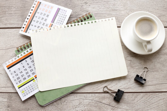 Still life, business, stationery or education concept: image of an open notebook with blank pages and a cup of coffee on a wooden background, ready to be added or mocked up. calendar