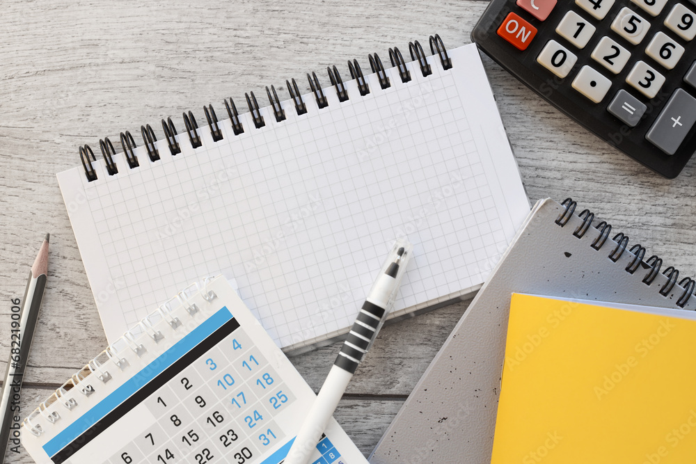 Poster pen on notepad and calculator isolated on wooden background