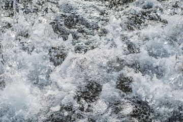 Detail of the splashes of water falling from the jet of a fountain on the surface. Frozen water movement. High speed. Horizontal.