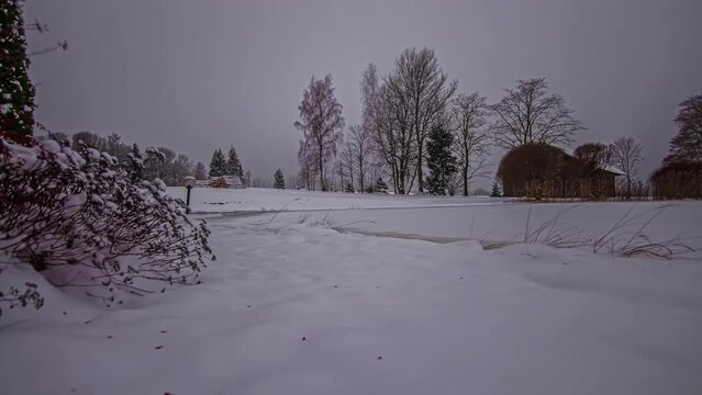 Low angle shot of snow covered farmlands along rural countryside in timelapse on a cloudy winter day.