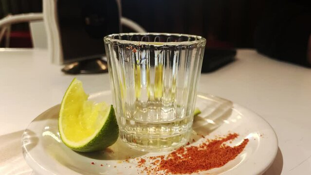 a glass of mezcal mescal mexico famous alcoholic beverage drink with lime lemon and pepper powder