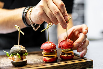 chef hand cooking set mini hamburgers, mini burgers on restaurant kitchen - obrazy, fototapety, plakaty