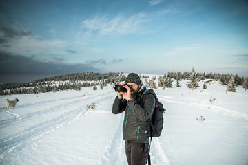 man and dog trekking in big snow in mountains in winter