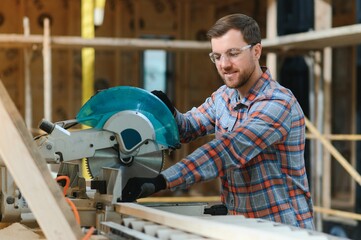 Wood cutting table with electric circular saw. Professional carpenter in uniform cutting wooden...