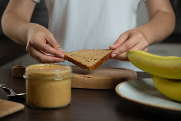 Woman preparing breakfast. Bread with peanut butter and banana.