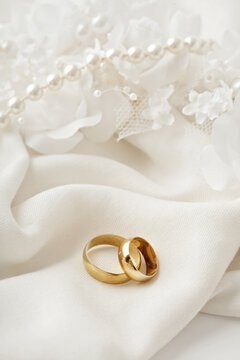golden wedding rings, pearls and white flowers