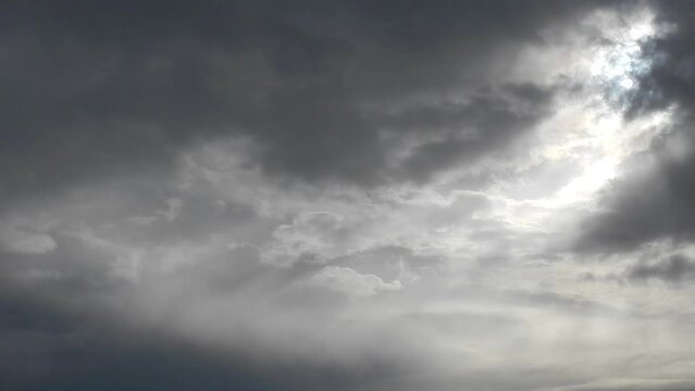 Gray cloudy sky background with moving clouds and sunlight - timelapse. Topics: weather, cloudiness, meteorology, climate