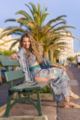 Fototapeta na wymiar Smiling woman in blue summer dress sitting on a bench