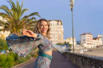 Happy woman in summer dress dancing while walking outdoors